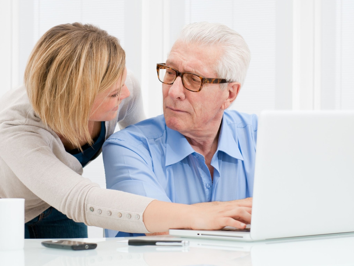 female helping mature male to use a computer