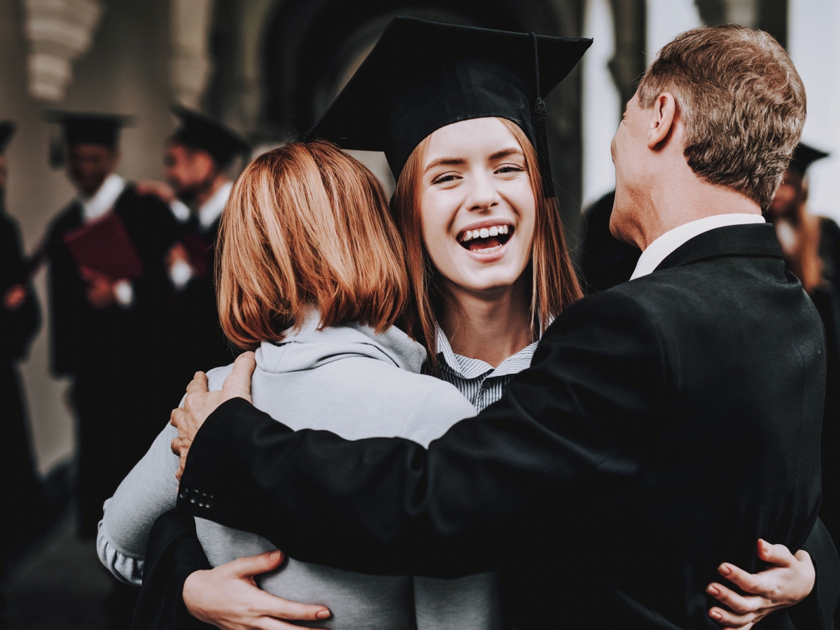 female student hugging parents at graduation